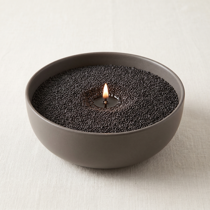 Fifty Shades of Musk black sand wax candle, lit, in a large round bowl